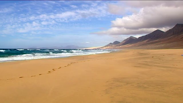 Arena dorada y montañas escarpadas en la interminable playa de Cofete