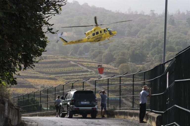 EL SAUZAL (TENERIFE), 10/10/2023.- Varios vecinos de El Sauzal observan como un helicóptero que trabaja en las labores de extinción del incendio forestal de Tenerife, carga agua. EFE/Alberto Valdés