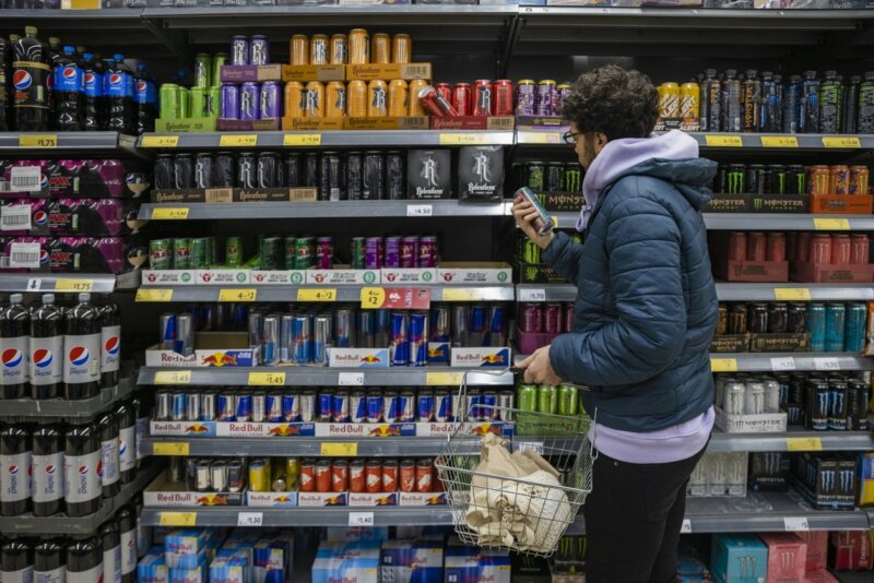 Un joven mira la sección de bebidas energéticas en el supermercado