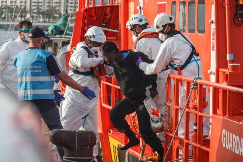 Varios trabajadores ayudan a una mujer a salir de la embarcación de Salvamento Marítimo ‘Guardamar Talía’ a su llegada al muelle de Arguineguín. Europa Press (Foto de ARCHIVO)