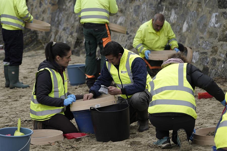 Operarios retiran los pellets o bolitas para fabricar plástico que aparecen en las playas de Asturias. Informa EFE
