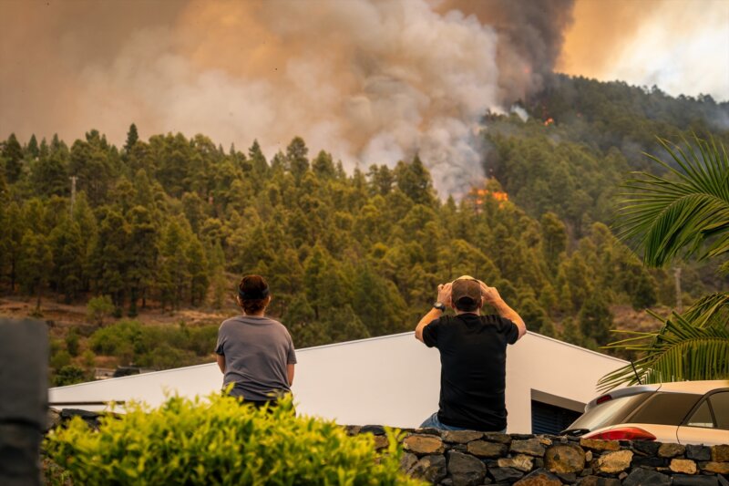 Dos vecinos observan las llamas del incendio forestal declarado en  la Palma, a 15 de julio de 2023, en Puntagorda, La Palma. Imagen Europa Press