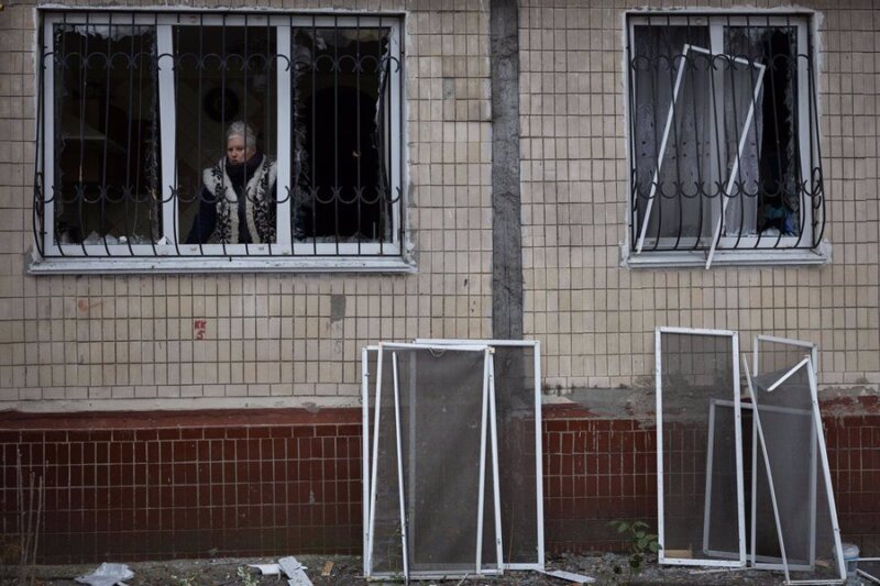 Una mujer mira por la ventana de un edificio dañado a causa de un ataque del Ejército de Rusia contra la capital de Ucrania, Kiev (archivo). Imagen: Oleksii Chumachenko/SOPA Images / DPA 