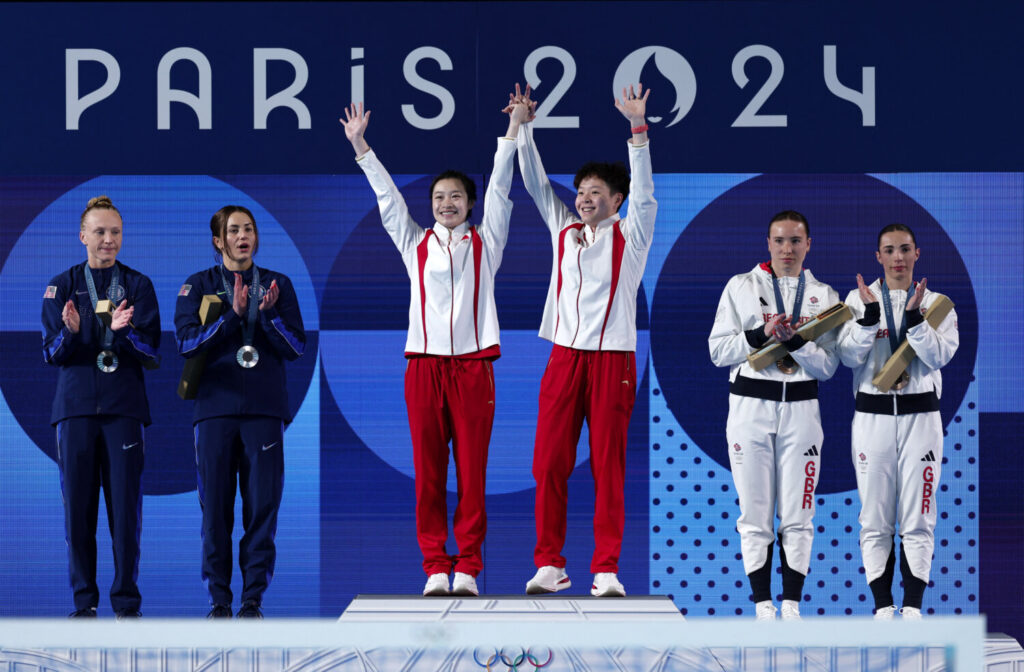 Buceo - Sincronización femenina 3m Ceremonia de Victoria de Springboard - Centro Acuático, Saint-Denis, Francia - 27 de julio de 2024. Los medallistas de bronce Yasmin Harper de Gran Bretaña y Scarlett Mew Jensen de Gran Bretaña ondean en el podio junto a los medallistas de oro Yani Chang de China y Yiwen Chen de China, y las medallistas de plata Kassidy Cook de Estados Unidos y Sarah Bacon de Estados Unidos. REUTERS/Leah Millis
