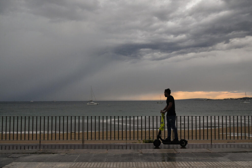 PALMA, 14/08/2024.- Un hombre pasea en patinete tras el paso de una Dana en Palma de Mallorca, este miércoles. Las tormentas que están atravesando Baleares este miércoles han obligado por seguridad a la cancelación de 9 vuelos y el desvío de otro más en los tres aeropuertos de Baleares, han informado a EFE fuentes de Aena. EFE/ Miquel A. Borràs