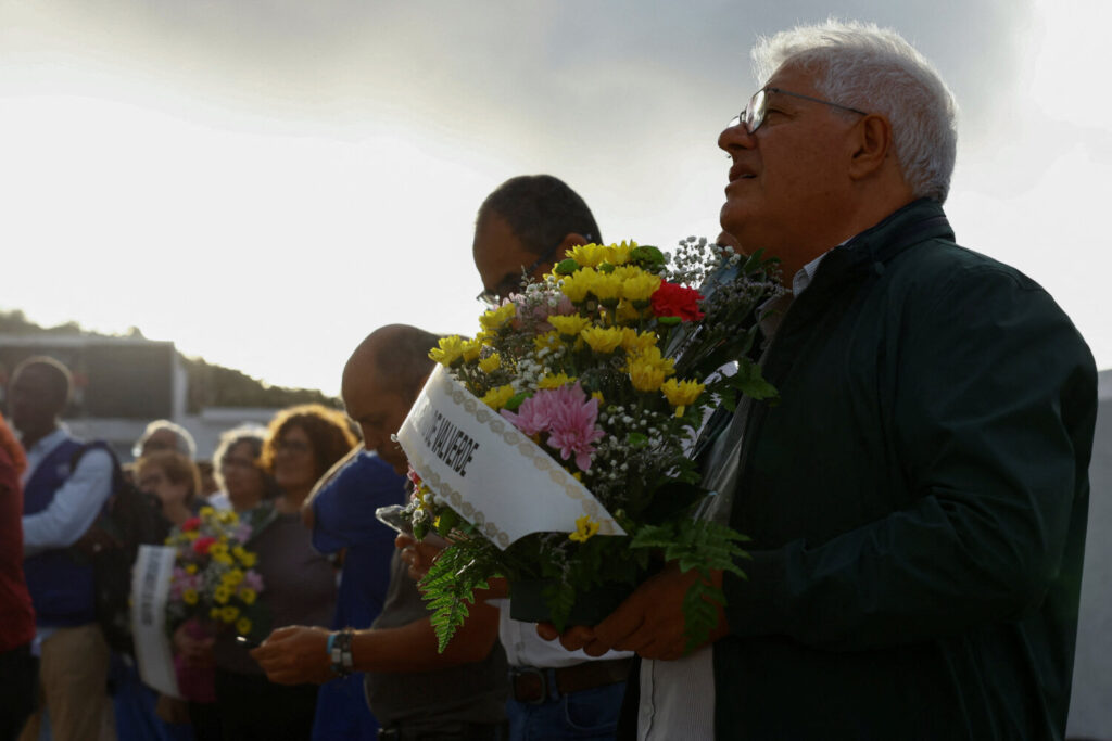 La gente sostiene flores durante el entierro de un migrante /REUTERS/Borja Suárez