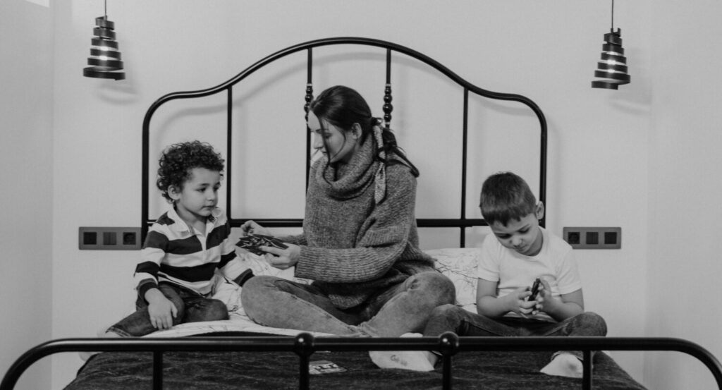 Foto de archivo de una madre y sus dos hijos sobre una cama.