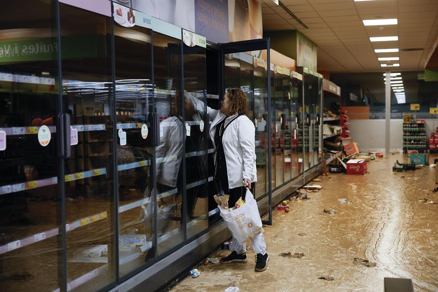 Una residente recoge alimentos en un supermercado en la localidad de Paiporta, Valencia, este jueves. La Comunitat Valenciana intenta recuperarse de la peor dana del siglo en España, que ha dejado casi un centenar de muertos en esa región, además de un inmenso escenario de daños en carreteras, calles e infraestructuras de numerosas localidades. EFE/ Biel Aliño