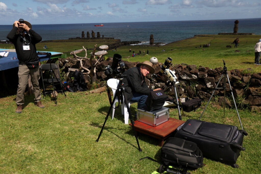 La gente observa el eclipse solar desde el área del monumento arqueológico de Tahai en el parque nacional Rapa Nui administrado por la comunidad nativa Mau Henua en la Isla de Pascua, Chile, 2 de octubre de 2024. REUTERS/Ivan Alvarado
