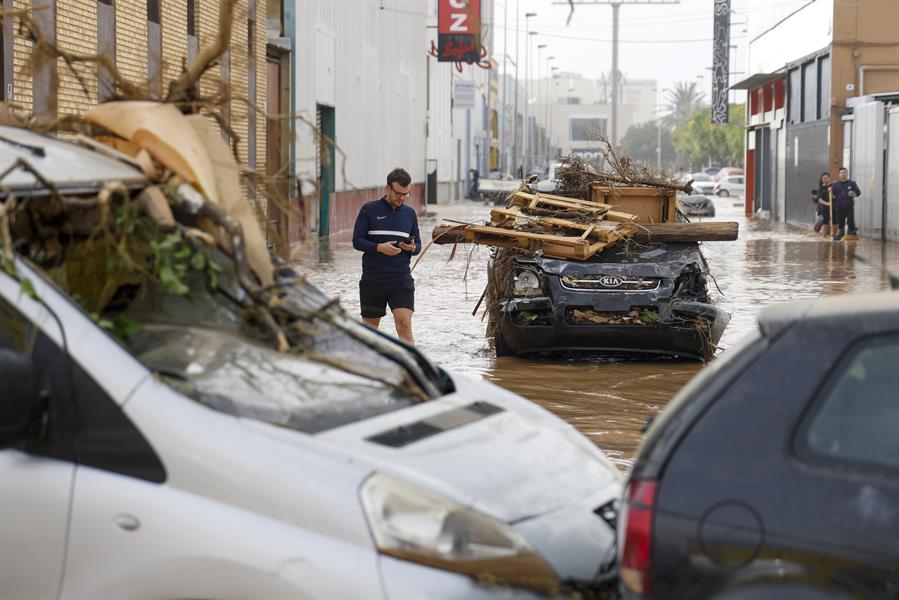 Varias personas transitan por el polígono industrial de Sedaví anegado a causa de las lluvias torrenciales de las últimas horas. EFE/Miguel Ángel Polo