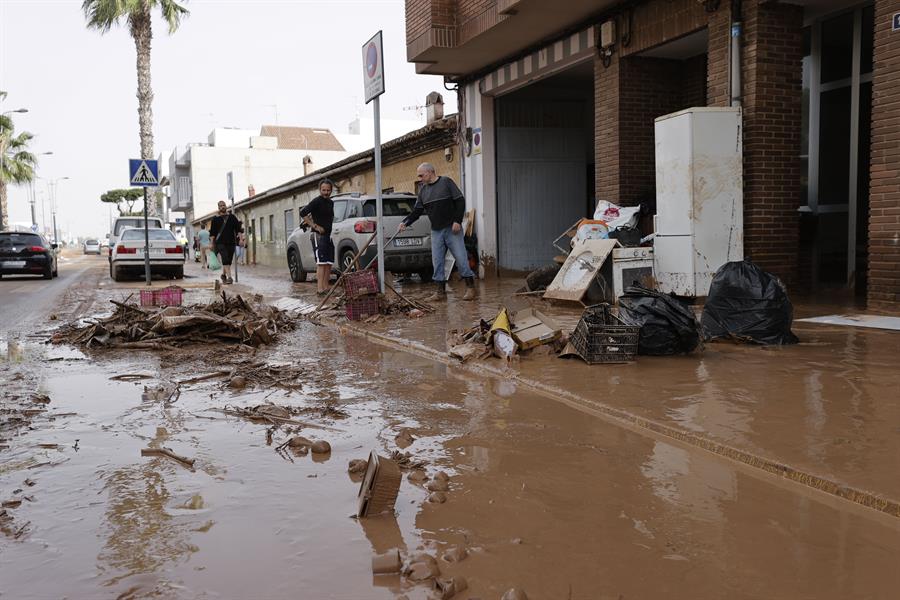 Varias personas limpian el lodo acumulado en sus viviendas a causa de las intensas lluvias por la fuerte dana que afecta especialmente el sur y el este de la península ibérica, este miércoles en Valencia. EFE/Manuel Bruque