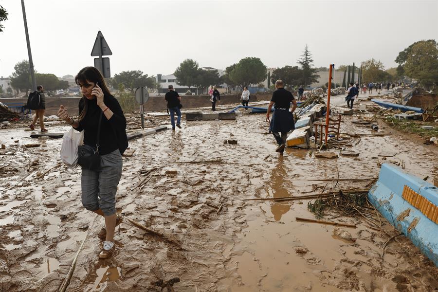 Una mujer camina entre el lodo acumulado por las intensas lluvias de la fuerte dana que afecta especialmente el sur y el este de la península ibérica, este miércoles en Picaña (Valencia). EFE/Biel Aliño