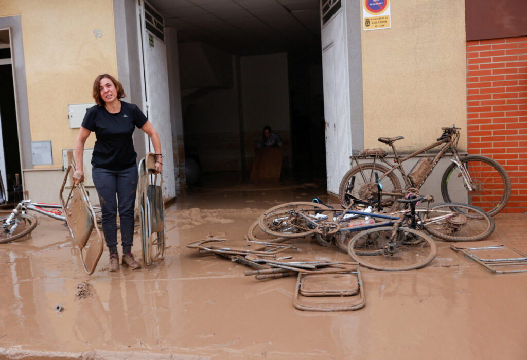 Una mujer lleva sillas plegables cubiertas de barro después de que las lluvias torrenciales causaran inundaciones en la Alcudia, región de Valencia, España, el 30 de octubre de 2024. REUTERS/Eva Manez