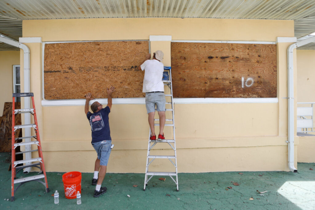 Dos vecinos protegen una casa antes de la llegada del huracán Milton, St. Pete Beach, Florida, EE.UU., 7 de octubre de 2024. REUTERS/Octavio Jones