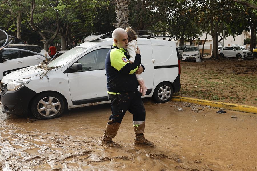 Un miembro de transporte sanitario con una niña tras las intensas lluvias de la fuerte dana que afecta especialmente el sur y el este de la península ibérica, este miércoles en Picaña (Valencia). EFE/Biel Aliño