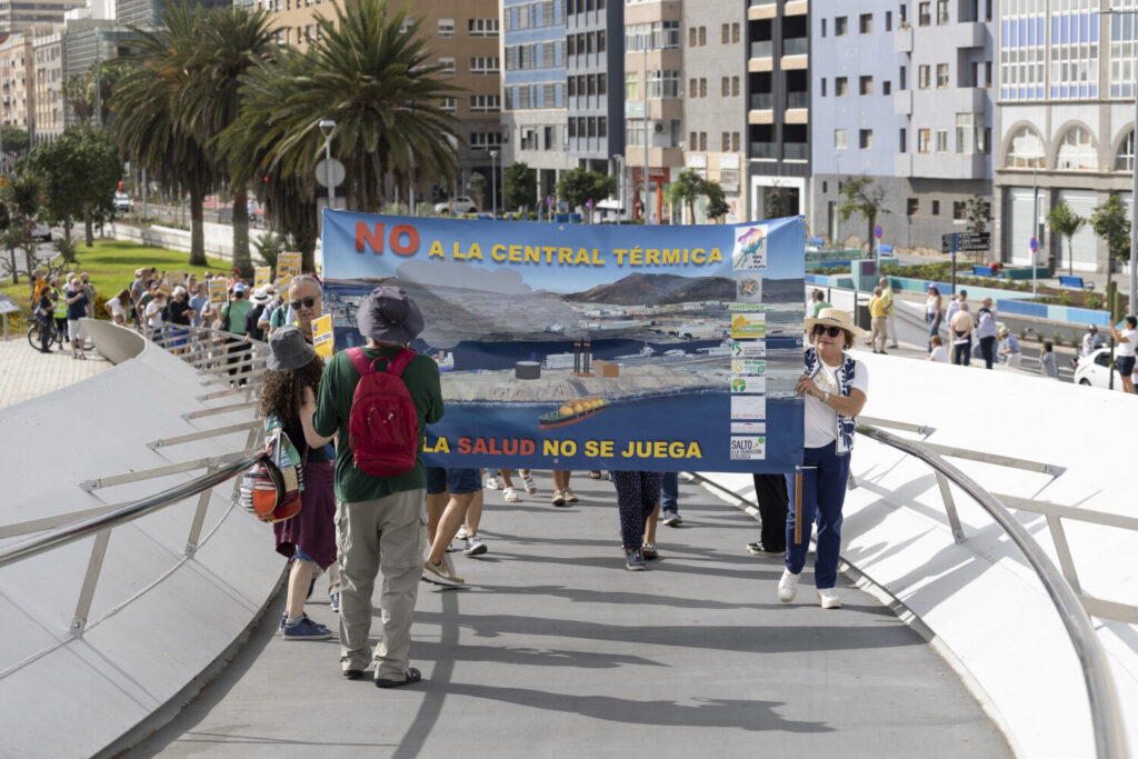 Vecinos, asociaciones ecologistas y colectivos sociales, protestan con pancartas sobre la pasarela Onda Atlántica