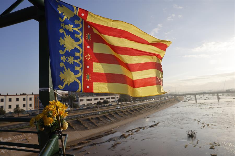 Una bandera de la Comunidad Valenciana junto a un ramillete de flores cuelga de la pasarela que va de Valencia hacia La Torre, este jueves. EFE/Ana Escobar