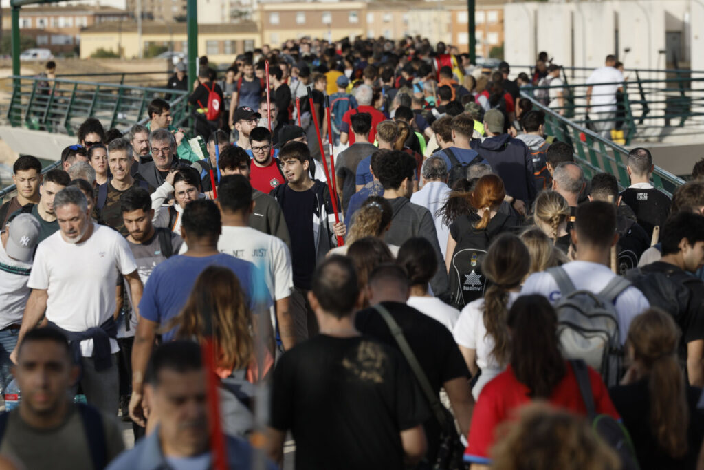 Cientos de personas cruzan la pasarela que da acceso al barrio de La Torre, en Valencia