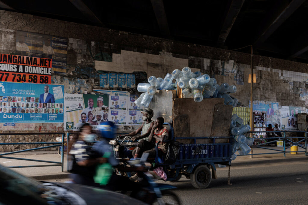 Un hombre viaja en un triciclo cargado de plástico para reciclar en un calle con carteles de campaña anteriores de las coaliciones Samm Sa Kaddu (Keep Its Word) y Senegaal Kese (sólo Senegal) para las próximas elecciones legislativas anticipadas en Dakar, Senegal. REUTERS/Zohra Bensemra