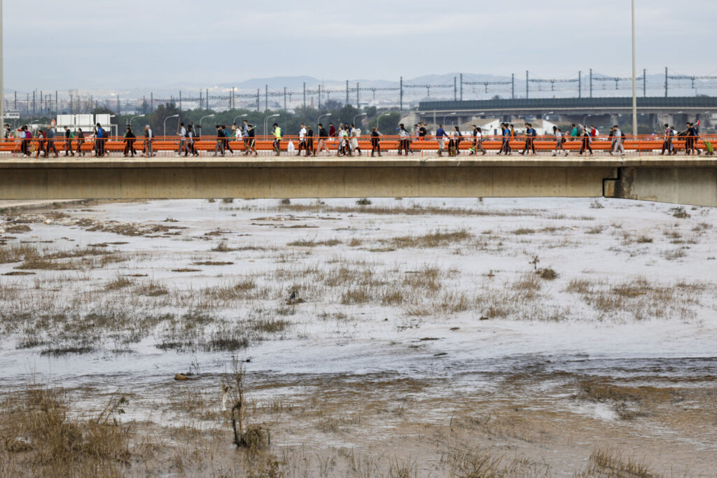 Voluntarios cruzan el río Turia desde Valencia en dirección a Paiporta para colaborar en las labores de limpieza y reconstrucción de las zonas afectadas por la dana, este domingo.