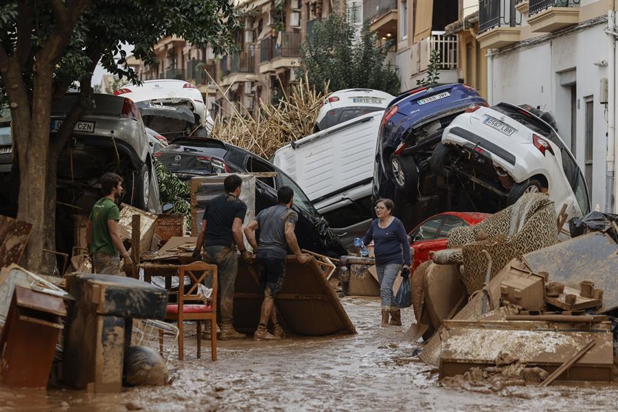 Vecinos de Paiporta trabajan en la limpieza de calles, locales y viviendas de la localidad junto a una montaña de vehículos arrastrados por la corriente, este viernes. Las víctimas mortales en la provincia de Valencia a causa de la devastadora dana ha aumentado este viernes hasta las 205, según el último recuento facilitado por el Centro de Emergencias de la Generalitat Valenciana. EFE/Biel Aliño