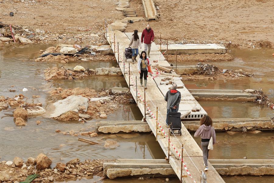 Vecinos cruzan una pasarela por el Barranco del Poyo para ir a comprar, en Picanya (Valencia), este sábado. EFE/ Villar López