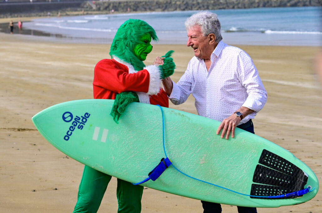 El Grinch de la Navidad surfea Las Canteras con espíritu solidario. Pedro Quevedo con el Grinch en Las Canteras/ LPA Visit.