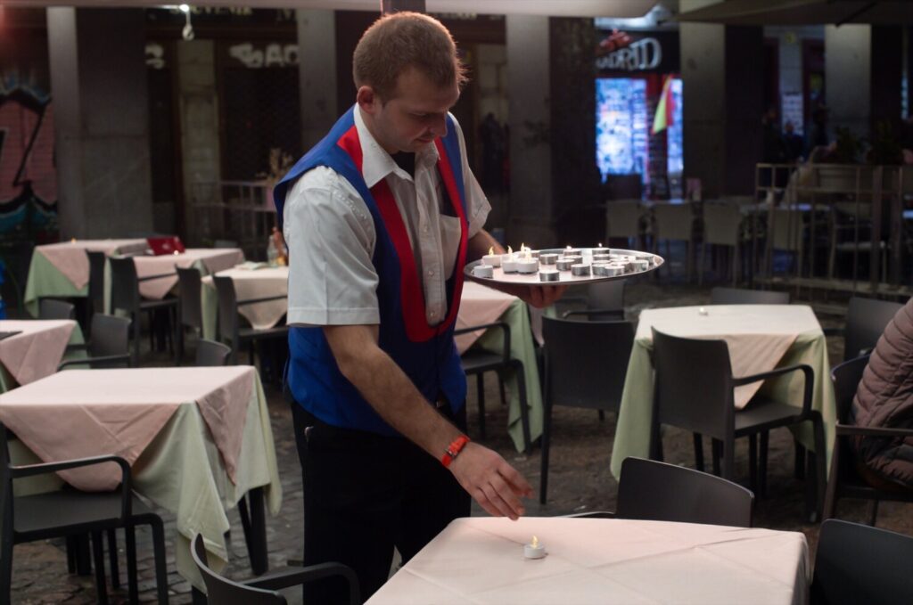 Imagen de archivo de un camarero encendiendo una vela en el salón de un restaurante.