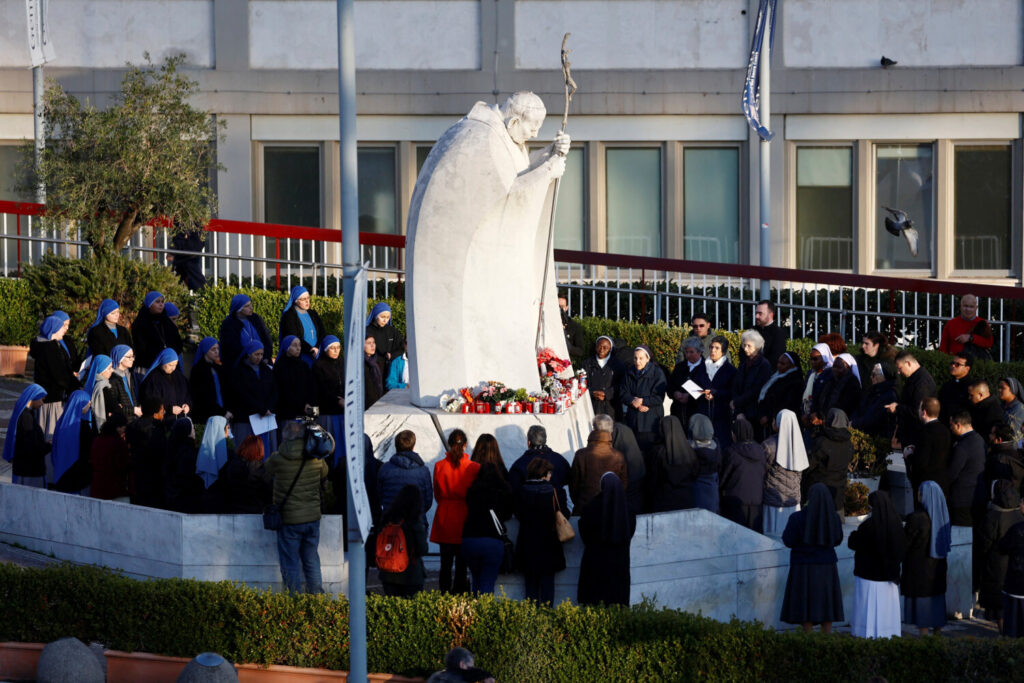 El papa Francisco en estado crítico tras una crisis respiratoria. Varias personas se reúnen para rezar el Rosario ante la estatua del difunto Papa Juan Pablo II en el exterior del Hospital Gemelli, donde el Papa Francisco está ingresado para recibir tratamiento, en Roma, Italia, 22 de febrero de 2025. REUTERS/Vincenzo Livieri.