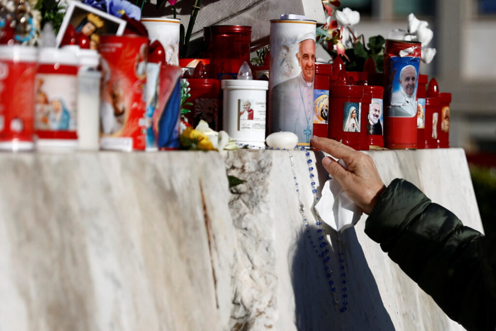 El papa Francisco en estado crítico tras una crisis respiratoria. Una mujer coloca un rosario en la estatua del difunto Papa Juan Pablo II en el exterior del Hospital Gemelli, donde el Papa Francisco está ingresado para recibir tratamiento, en Roma, Italia, 22 de febrero de 2025. REUTERS/Vincenzo Livieri.