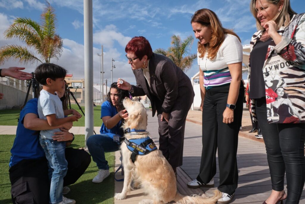 Yogui recibe la primera chapa acreditativa de perro de asistencia. Candelaria Delgado entregando la chapa acreditativa de perro de asistencia a Benjamín y su perro Yogui/ Gobierno de Canarias.